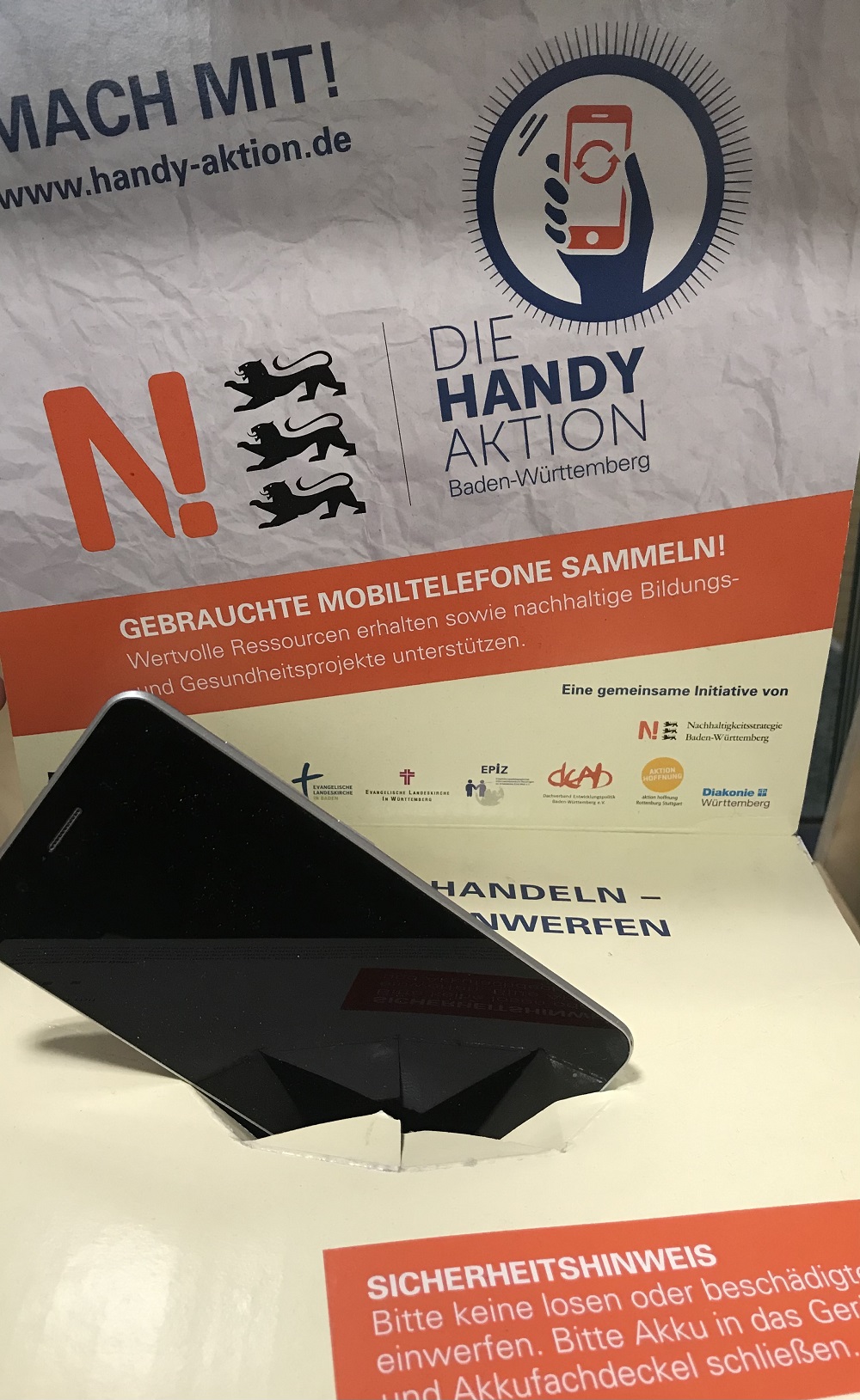 Ein Smartphone wird in die Aktionsbox der Handy-Aktion eingeworfen